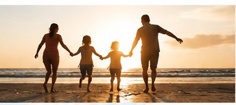 A family walking together on a beach at sunset